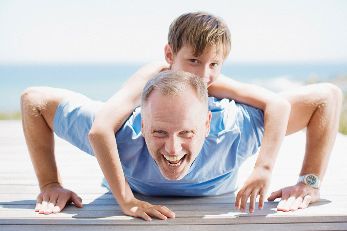 Padre haciendo flexiones con hijo sobre su espalda