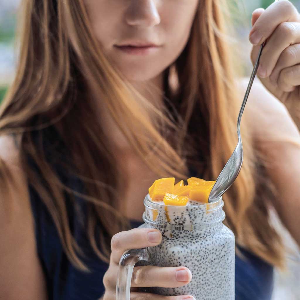 Mujer disfrutando pudding de chía sin lactosa, rico en omega-3 y fibra para el bienestar diario